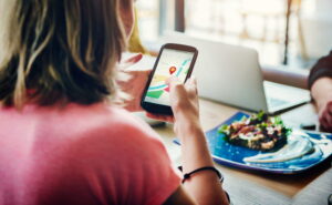 Persona buscando un negocio local en Google Maps desde el móvil con resultados destacados en el mapa